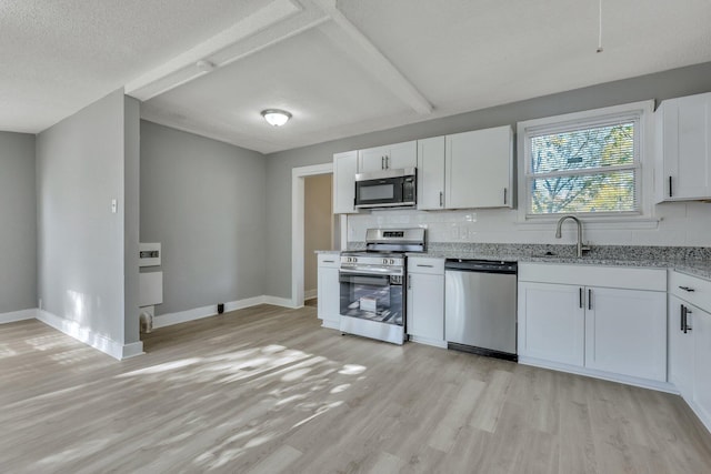 kitchen featuring a sink, light wood-style floors, tasteful backsplash, and appliances with stainless steel finishes