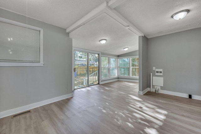 unfurnished room featuring visible vents, a textured ceiling, baseboards, and wood finished floors