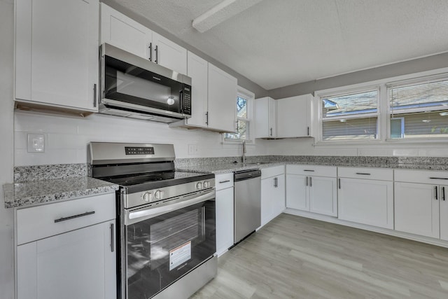 kitchen with light wood-style flooring, white cabinetry, stainless steel appliances, and a sink