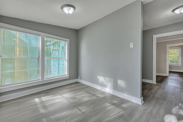 spare room with wood finished floors, baseboards, and a textured ceiling