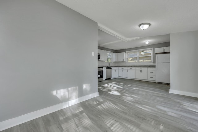 kitchen featuring baseboards, appliances with stainless steel finishes, and white cabinetry