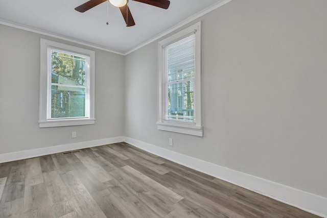 spare room with wood finished floors, visible vents, baseboards, ceiling fan, and ornamental molding