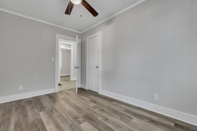 empty room featuring baseboards, wood finished floors, and ornamental molding