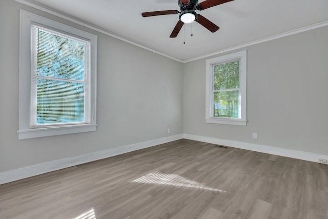 empty room with visible vents, a ceiling fan, wood finished floors, crown molding, and baseboards