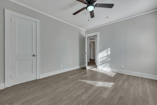 empty room featuring wood finished floors, baseboards, and ornamental molding