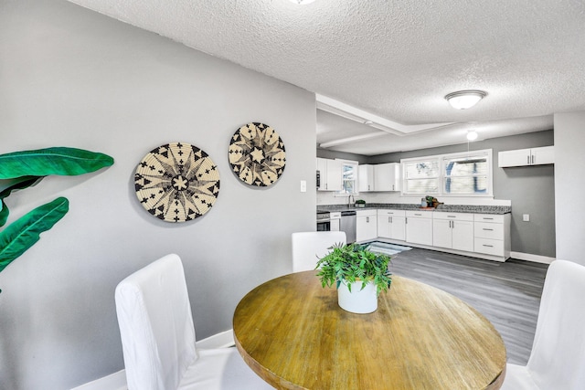 dining room with baseboards, a textured ceiling, and wood finished floors