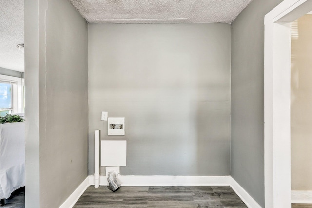 laundry room featuring dark wood-style floors, laundry area, a textured ceiling, and baseboards