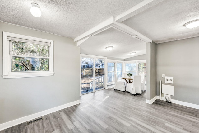 interior space with visible vents, baseboards, a textured ceiling, and wood finished floors