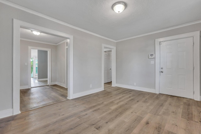 empty room featuring baseboards, wood finished floors, and crown molding