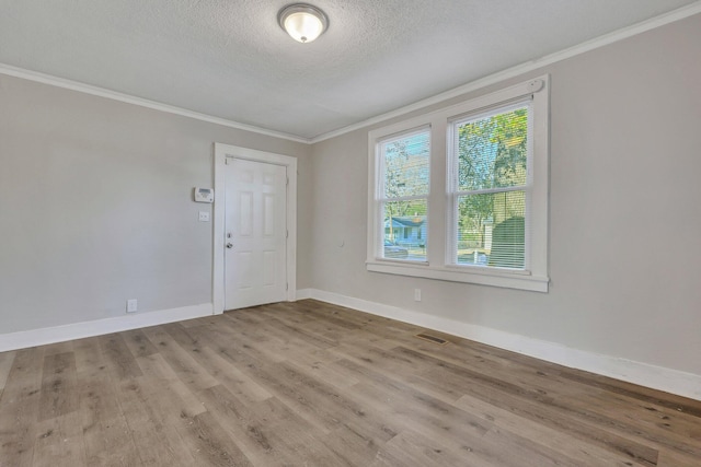 empty room with visible vents, baseboards, wood finished floors, and ornamental molding