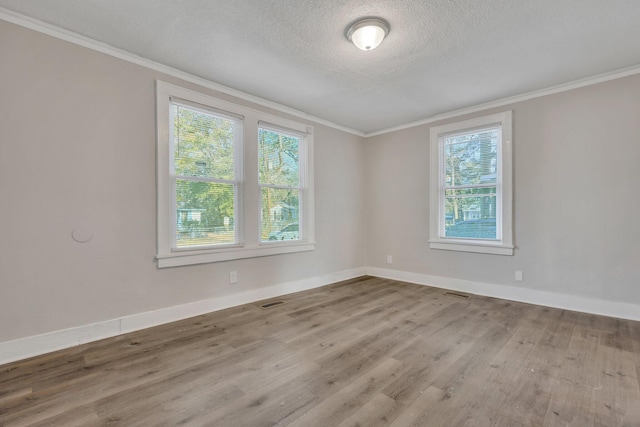 empty room with a textured ceiling, wood finished floors, and ornamental molding