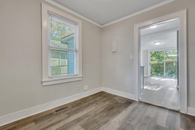 empty room with visible vents, crown molding, baseboards, and wood finished floors