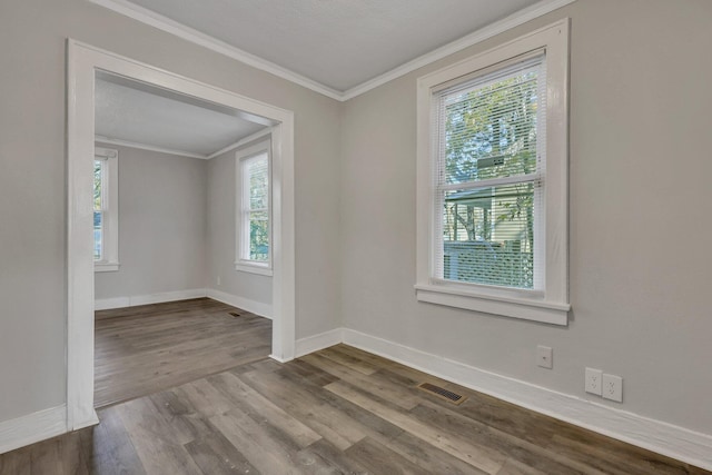 spare room with visible vents, crown molding, baseboards, and wood finished floors