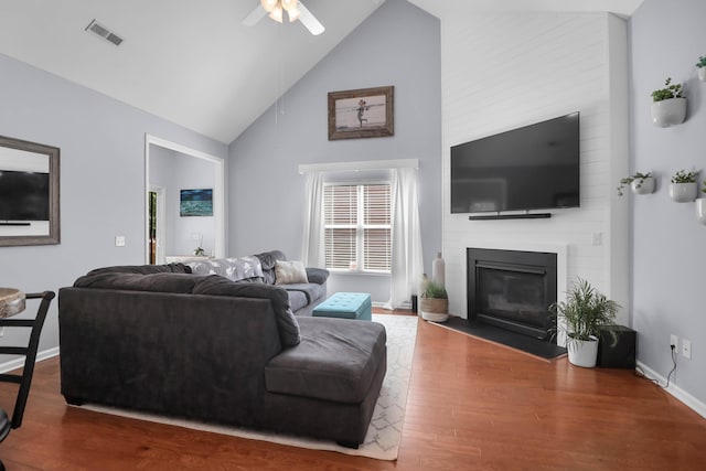 living area with high vaulted ceiling, a ceiling fan, wood finished floors, a fireplace, and baseboards