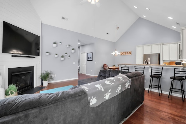 living area featuring high vaulted ceiling, dark wood finished floors, a fireplace, ceiling fan, and recessed lighting