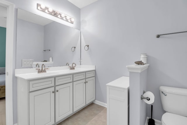 bathroom featuring toilet, connected bathroom, double vanity, and baseboards