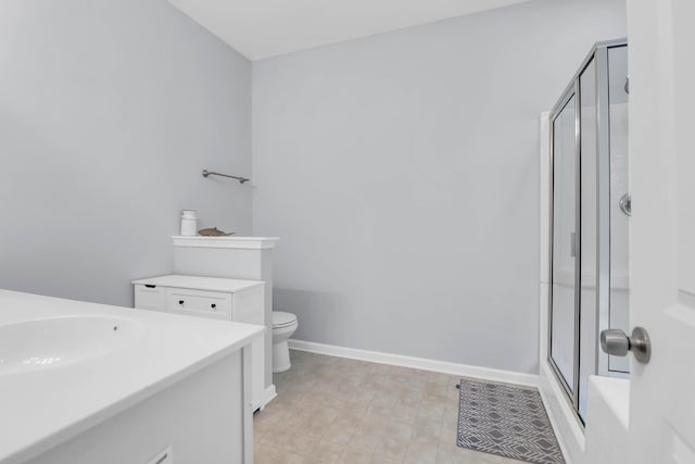 bathroom with a shower stall, baseboards, vanity, and toilet