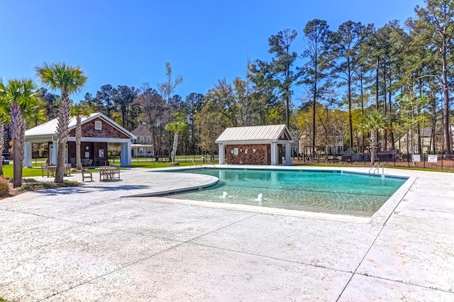 community pool with a gazebo, a patio, fence, and view of wooded area