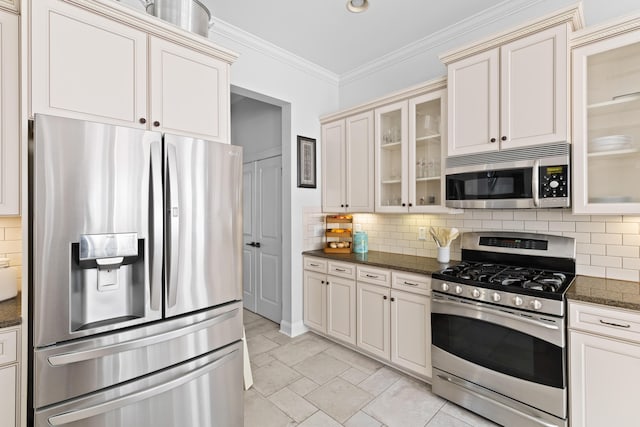 kitchen with crown molding, appliances with stainless steel finishes, decorative backsplash, and dark stone counters