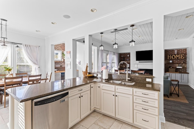 kitchen featuring pendant lighting, sink, dark stone countertops, plenty of natural light, and stainless steel dishwasher