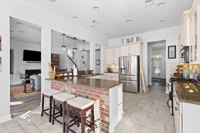 kitchen featuring stainless steel appliances, a kitchen breakfast bar, kitchen peninsula, and dark stone countertops