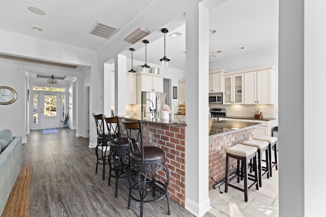 kitchen featuring tasteful backsplash, light wood-type flooring, appliances with stainless steel finishes, a kitchen breakfast bar, and pendant lighting