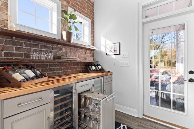 bar with wooden counters, gray cabinetry, wine cooler, brick wall, and dark hardwood / wood-style flooring