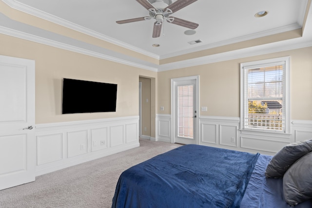 bedroom with light carpet, a tray ceiling, crown molding, and ceiling fan