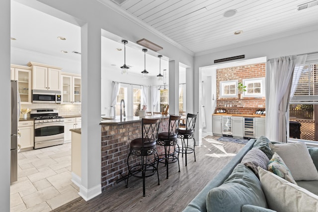 kitchen featuring wine cooler, hanging light fixtures, crown molding, and appliances with stainless steel finishes