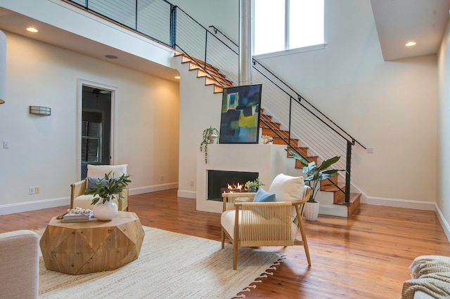 living room with a towering ceiling and hardwood / wood-style flooring