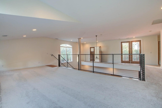 carpeted spare room featuring lofted ceiling and plenty of natural light