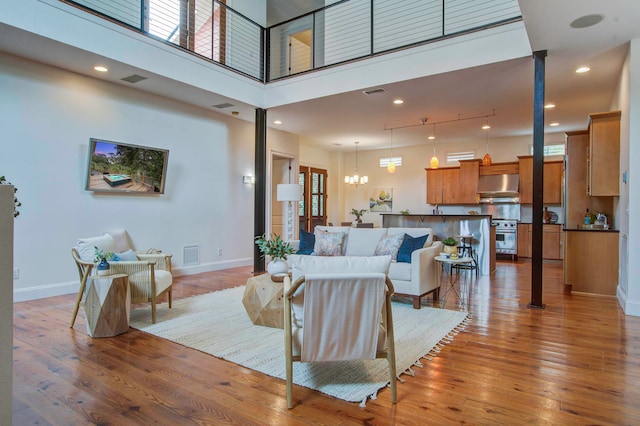 living room with light hardwood / wood-style floors, a towering ceiling, and plenty of natural light