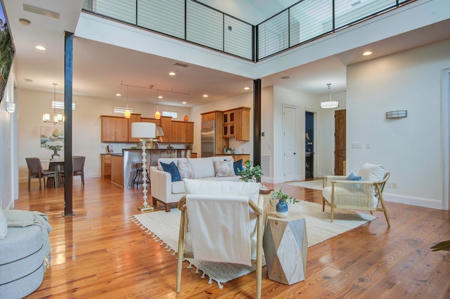 living room featuring a towering ceiling, light hardwood / wood-style floors, and a chandelier