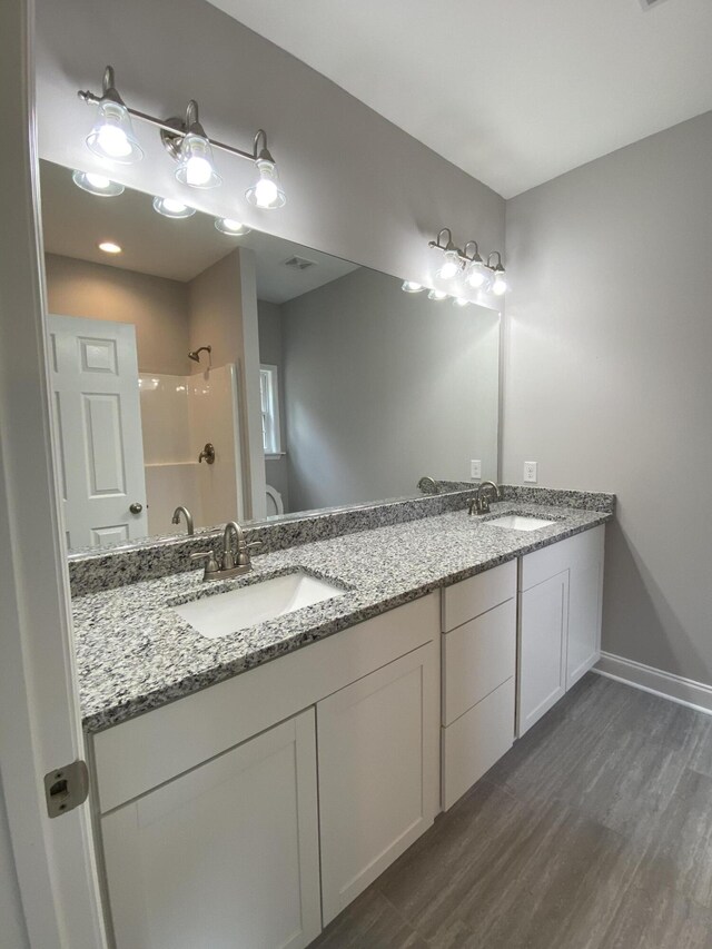 110A Dukes St, Saint George, SC 29477 - bathroom with a shower, double vanity, wood finished floors, and baseboards