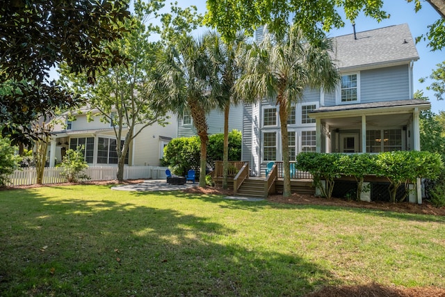 1977 Pierce St, Charleston, SC 29492 - rear view of house featuring a wooden deck, a sunroom, a lawn, fence, and a shingled roof
