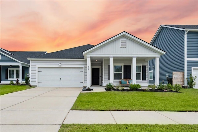 view of front of home with a yard, a porch, and a garage