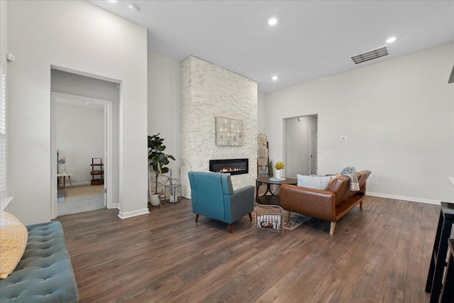 living room with dark wood-type flooring and a stone fireplace