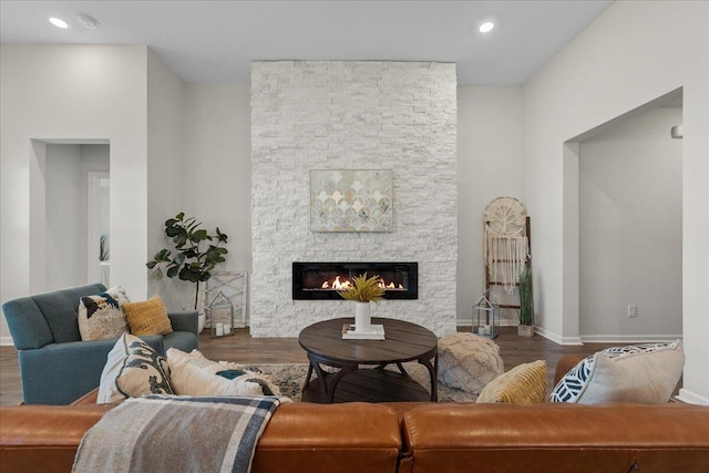 living room featuring dark wood-type flooring and a stone fireplace