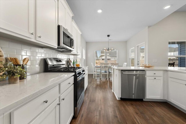 kitchen with white cabinets, a healthy amount of sunlight, appliances with stainless steel finishes, dark hardwood / wood-style floors, and pendant lighting