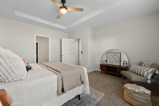 carpeted bedroom featuring a tray ceiling and ceiling fan