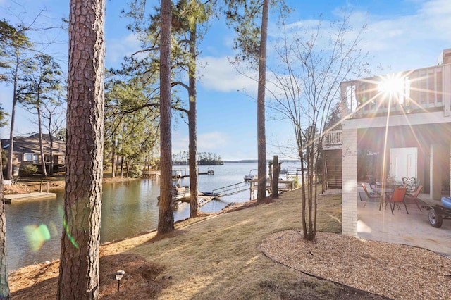 view of yard with a boat dock, a patio, and a water view