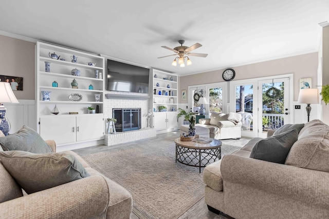 living room featuring ceiling fan, crown molding, a fireplace, and french doors