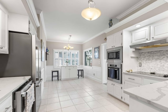 kitchen with appliances with stainless steel finishes, crown molding, a notable chandelier, white cabinets, and hanging light fixtures