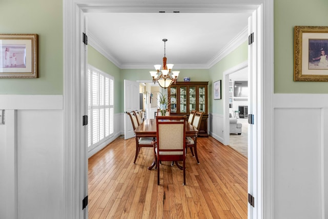 dining space featuring a chandelier, light hardwood / wood-style floors, and crown molding