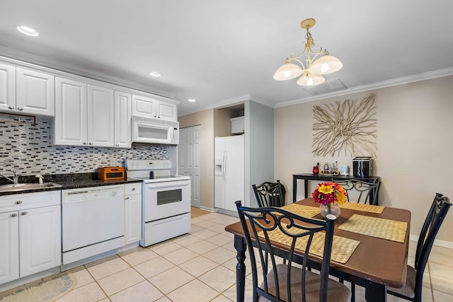 kitchen with white appliances, an inviting chandelier, sink, light tile patterned floors, and white cabinetry