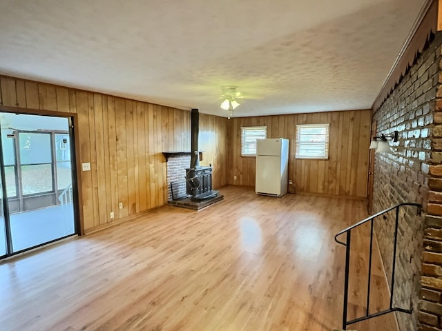 unfurnished living room featuring hardwood / wood-style flooring, a wood stove, and ceiling fan