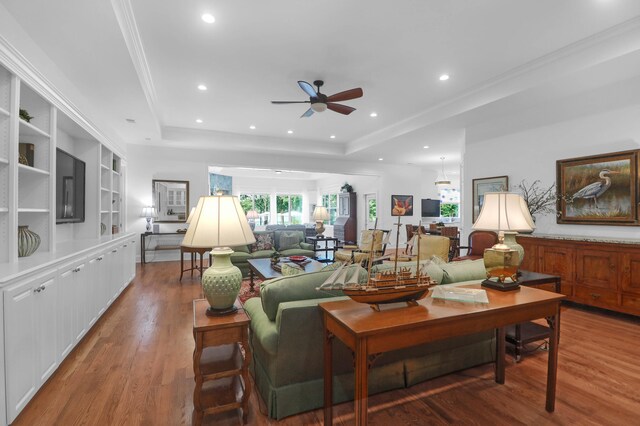 living room featuring ornamental molding, wood-type flooring, and a raised ceiling