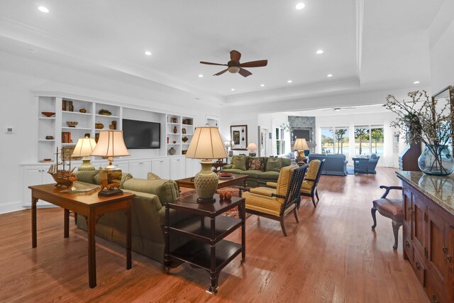 living room featuring a tray ceiling, wood-type flooring, and ceiling fan