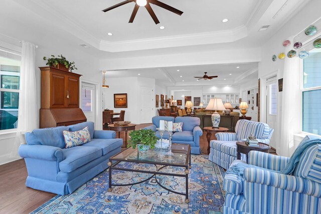 living room with ornamental molding, wood-type flooring, and a tray ceiling