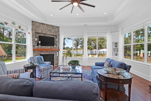 sunroom / solarium with a tray ceiling, a stone fireplace, and ceiling fan